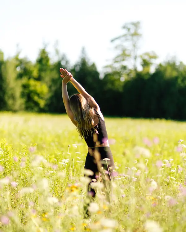 Side stretch with arms overhead in a meadow of wildflowers